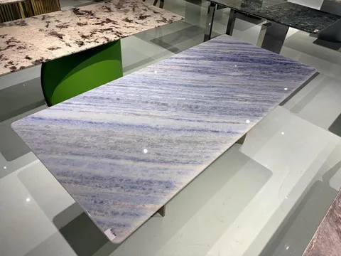 blue stone dining table, with a rectangular top and banded onyx-like striping, in a showroom