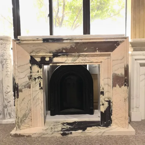 White Volakas marble fireplace surround, with bold veining and a reflective finish, in a showroom