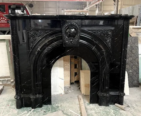White Volakas marble fireplace surround, with an arched opening and fine veining, in a workshop