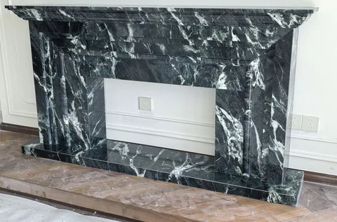 green stone fireplace surround, with stepped tiers and bold veining, against a pale background