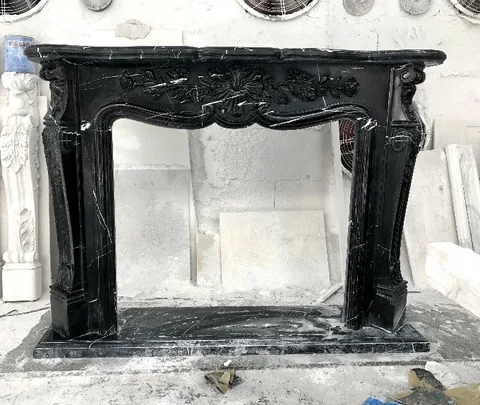White Volakas marble fireplace surround, with carved scrollwork and fine veining, in a workshop