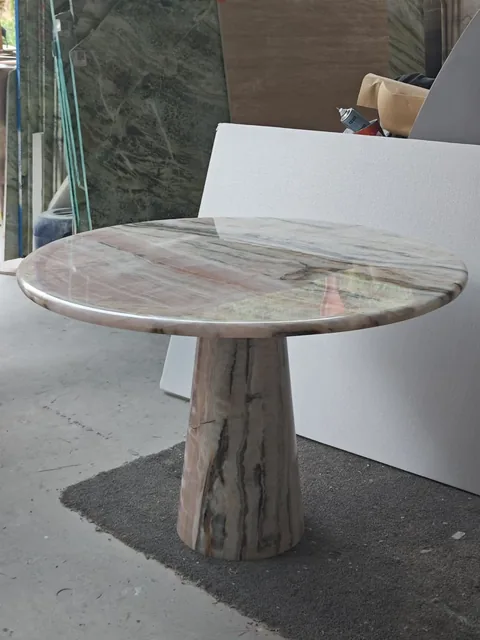 cream-beige stone coffee table, with bold veining and a reflective finish, in a workshop