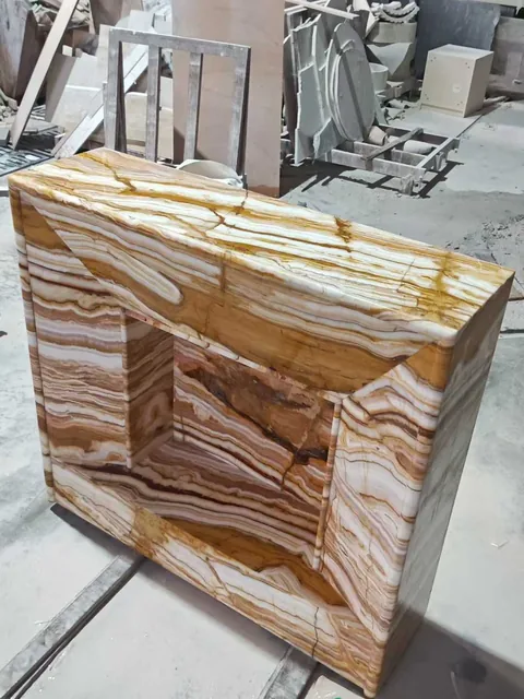 cream-beige stone side table, with banded onyx-like striping and a reflective finish, in a workshop
