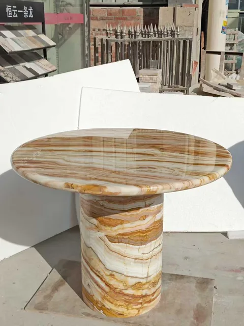 cream-beige stone side table, with a central pedestal base and banded onyx-like striping, in a workshop