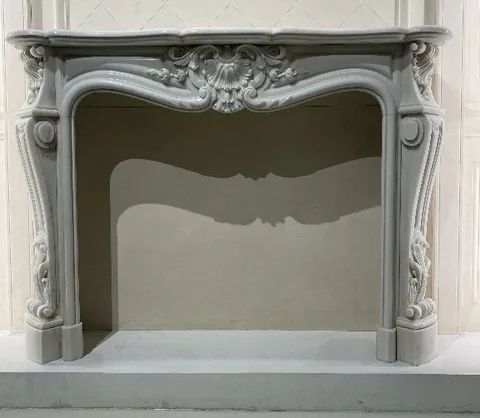 White Volakas marble fireplace surround, with a plain surface and a reflective finish, in a showroom