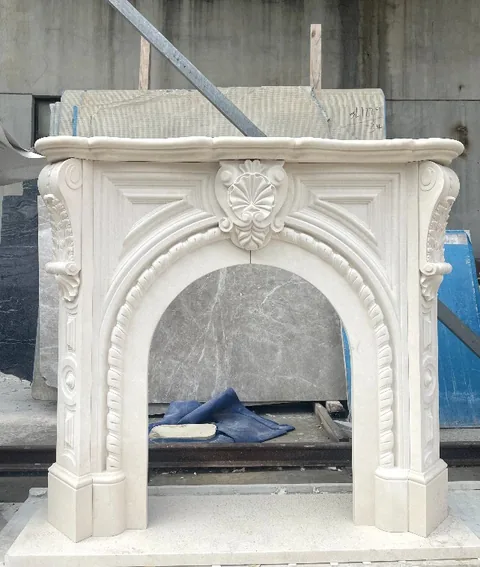 White Volakas marble fireplace surround, with an arched opening and a plain surface, in a workshop