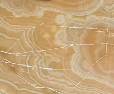 gold stone slab, with banded onyx-like striping and a reflective finish, in a close surface view