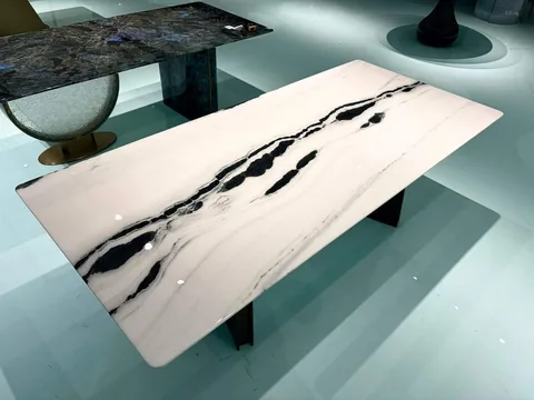 cream-beige stone dining table, with a rectangular top and bold veining, in a showroom