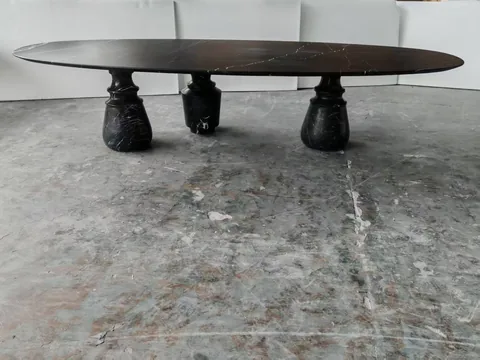 black stone dining table, with an oval top and fine veining, in a workshop