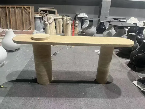 cream-beige stone coffee table, with twin supporting bases and linear travertine grain, in a workshop