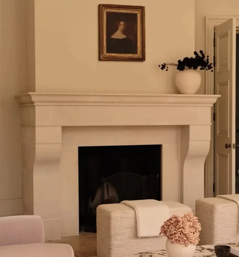 White Volakas marble fireplace surround, with a plain surface, in a furnished room