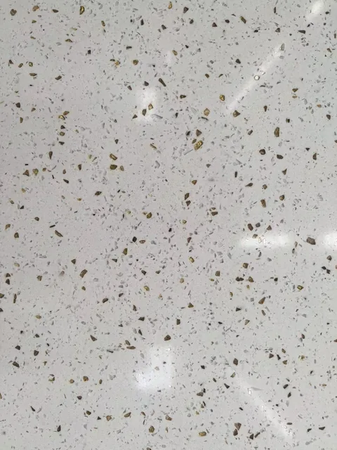 white engineered stone slab, with a speckled texture and a reflective finish, in a close surface view