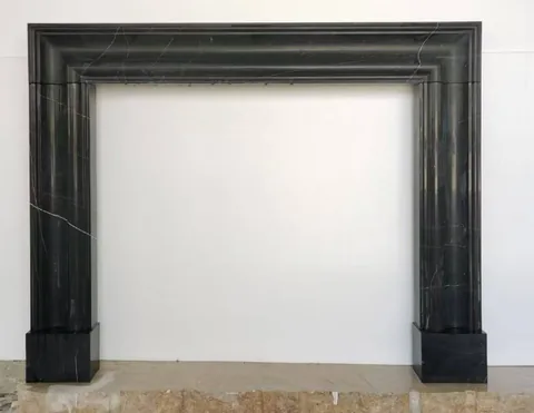 White Volakas marble fireplace surround, with stepped tiers and fine veining, on a plain backdrop