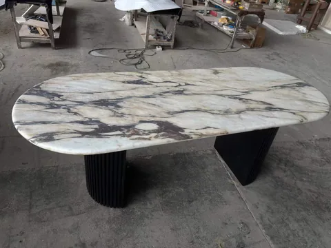 white stone dining table, with twin supporting bases and bold veining, in a workshop