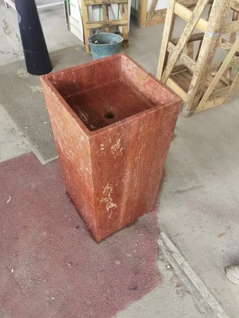 rose-red stone landscape feature, with a stone planter and linear travertine grain, in a workshop