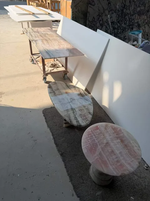 rose-red stone coffee table, with banded onyx-like striping and a reflective finish, in a workshop