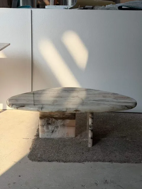 white stone coffee table, with twin supporting bases and banded onyx-like striping, in a workshop