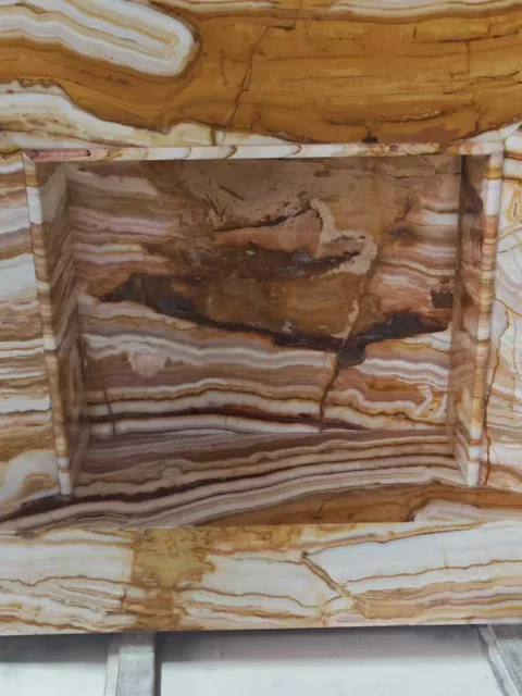 brown stone fireplace surround, with banded onyx-like striping and a reflective finish, in a close surface view