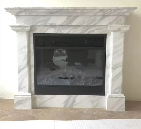 White Volakas marble fireplace surround, with fine veining, in a furnished room
