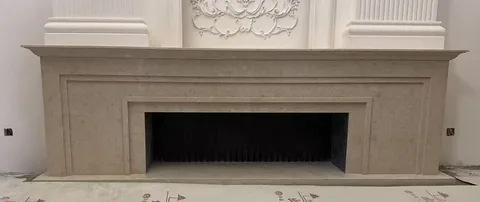 White Volakas marble fireplace surround, with stepped tiers and cloudy mottling, against a pale background