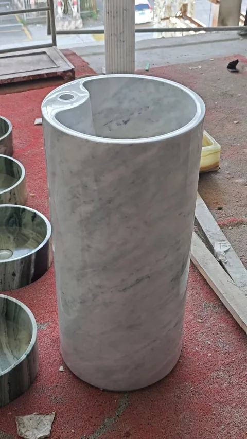 gray stone sink, with a form carved from solid stone and cloudy mottling, in a workshop