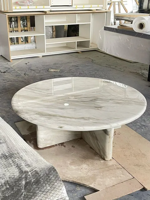 white stone coffee table, with fine veining and a reflective finish, in a workshop