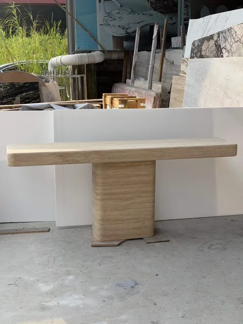 cream-beige stone console table, with wood-like grain and a matte finish, in a workshop
