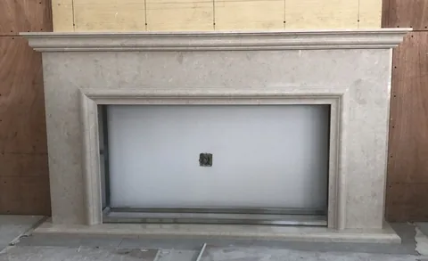 White Volakas marble fireplace surround, with cloudy mottling and a soft satin finish, in a workshop