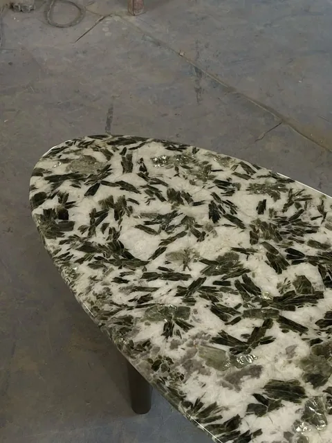 white stone coffee table, with an oval top and angular breccia fragments, in a workshop