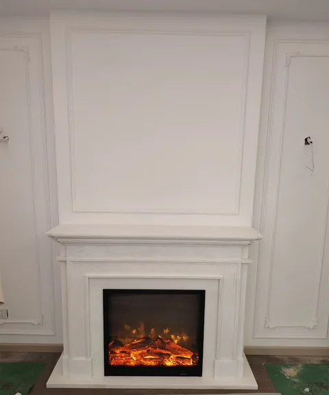 White Volakas marble fireplace surround, with fine veining, in a furnished room