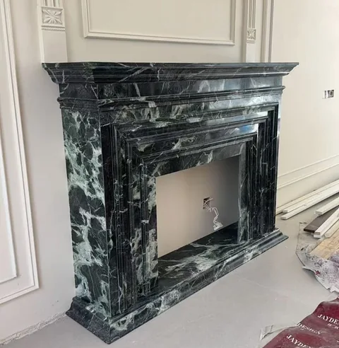 black stone fireplace surround, with stepped tiers and bold veining, in a workshop