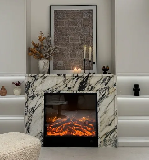 White Volakas marble fireplace surround, with bold veining and a reflective finish, in a furnished room
