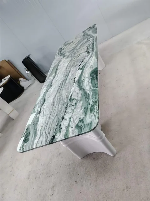 white stone dining table, with bold veining and a reflective finish, in a workshop