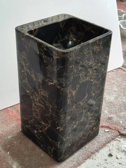 black stone sink, with a form carved from solid stone and bold veining, in a workshop