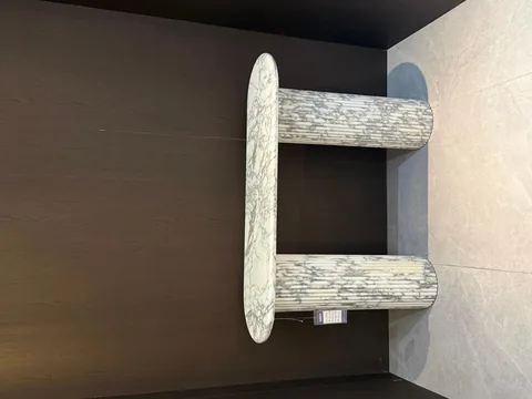 white stone console table, with twin supporting bases and fine veining, in a showroom