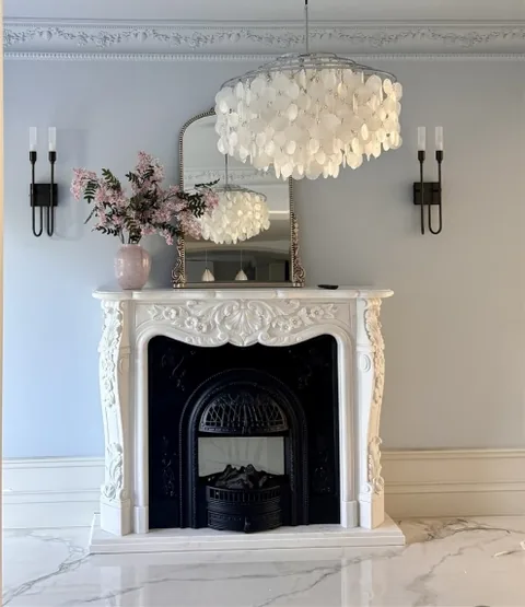 White Volakas marble fireplace surround, with fine veining, shown from a frontal view with room decor nearby