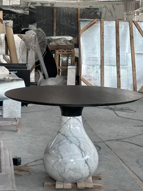 white stone dining table, with a central pedestal base and bold veining, in a workshop