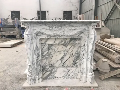 White Volakas marble fireplace surround, with bold veining, in a workshop