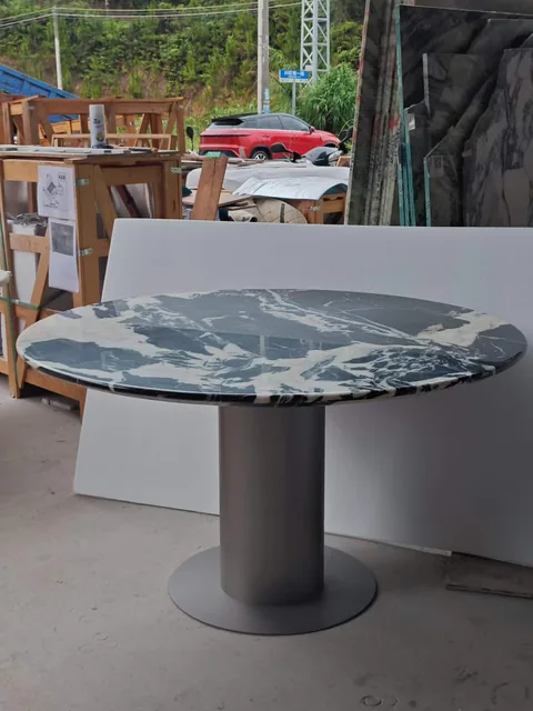 blue stone dining table, with bold veining and a reflective finish, in a workshop
