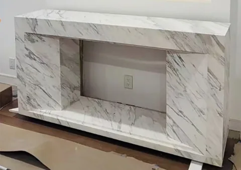 White Volakas marble fireplace surround, with a straight recessed opening and fine veining, in a workshop