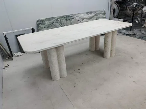 white stone dining table, with twin supporting bases and fine veining, in a workshop