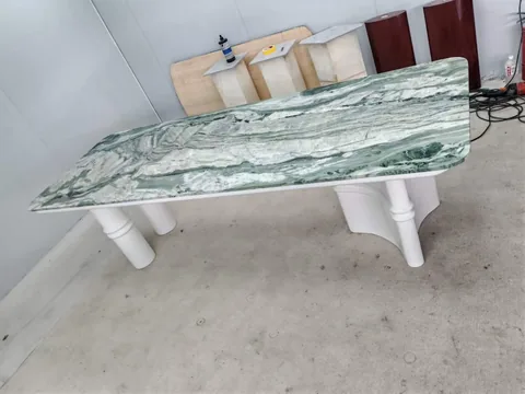 white stone dining table, with twin supporting bases and bold veining, in a workshop