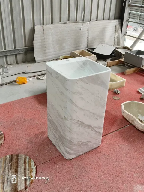 white stone sink, with a form carved from solid stone and fine veining, in a workshop