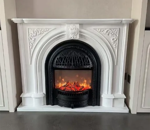 White Volakas marble fireplace surround, with an arched opening and a plain surface, in a furnished room