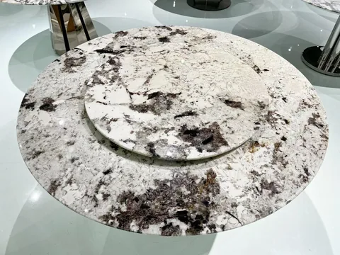 white stone dining table, with a round top and cloudy mottling, in a showroom