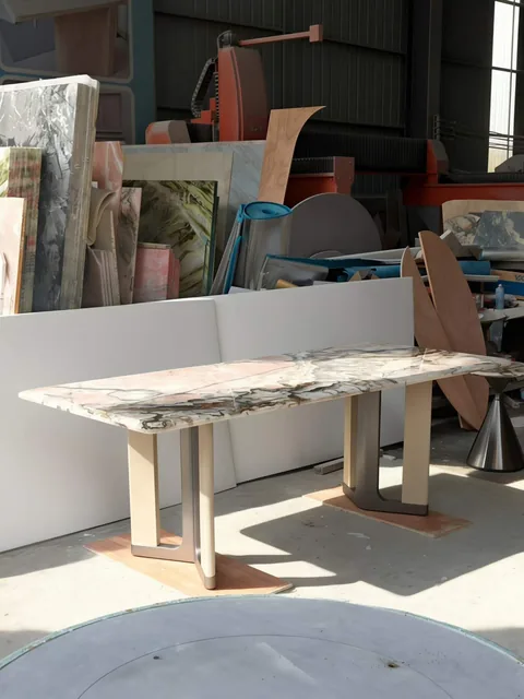 white stone dining table, with twin supporting bases and bold veining, in a workshop
