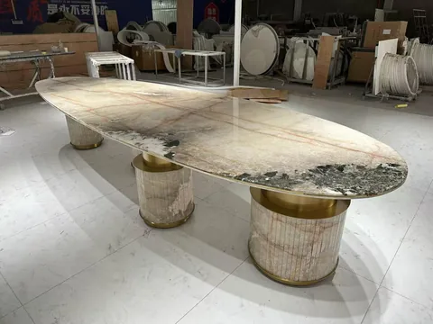 cream-beige stone dining table, with fine veining and a reflective finish, in a workshop