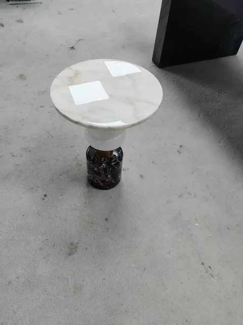 white stone side table, with a round top and fine veining, in a workshop