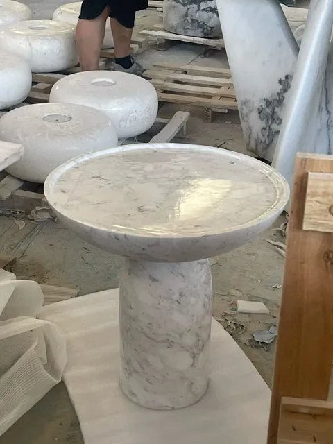 white stone side table, with a central pedestal base and fine veining, in a workshop
