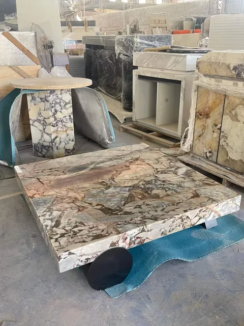 cream-beige stone coffee table, with a rectangular top and bold veining, in a workshop